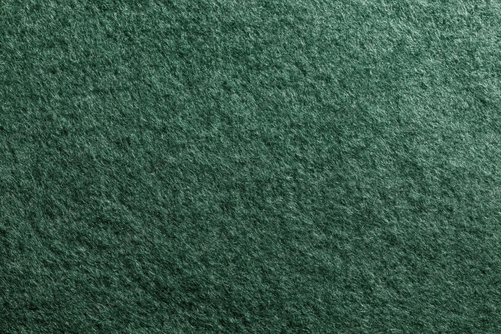 Close-up flat lay of dark forest green felt or suede fabric surface
