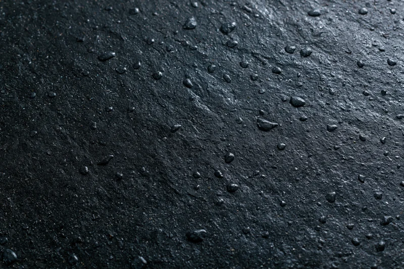 Wet dark concrete surface with water droplets in flat lay closeup
