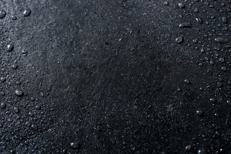 Wet dark concrete surface with water droplets in flat lay arrangement