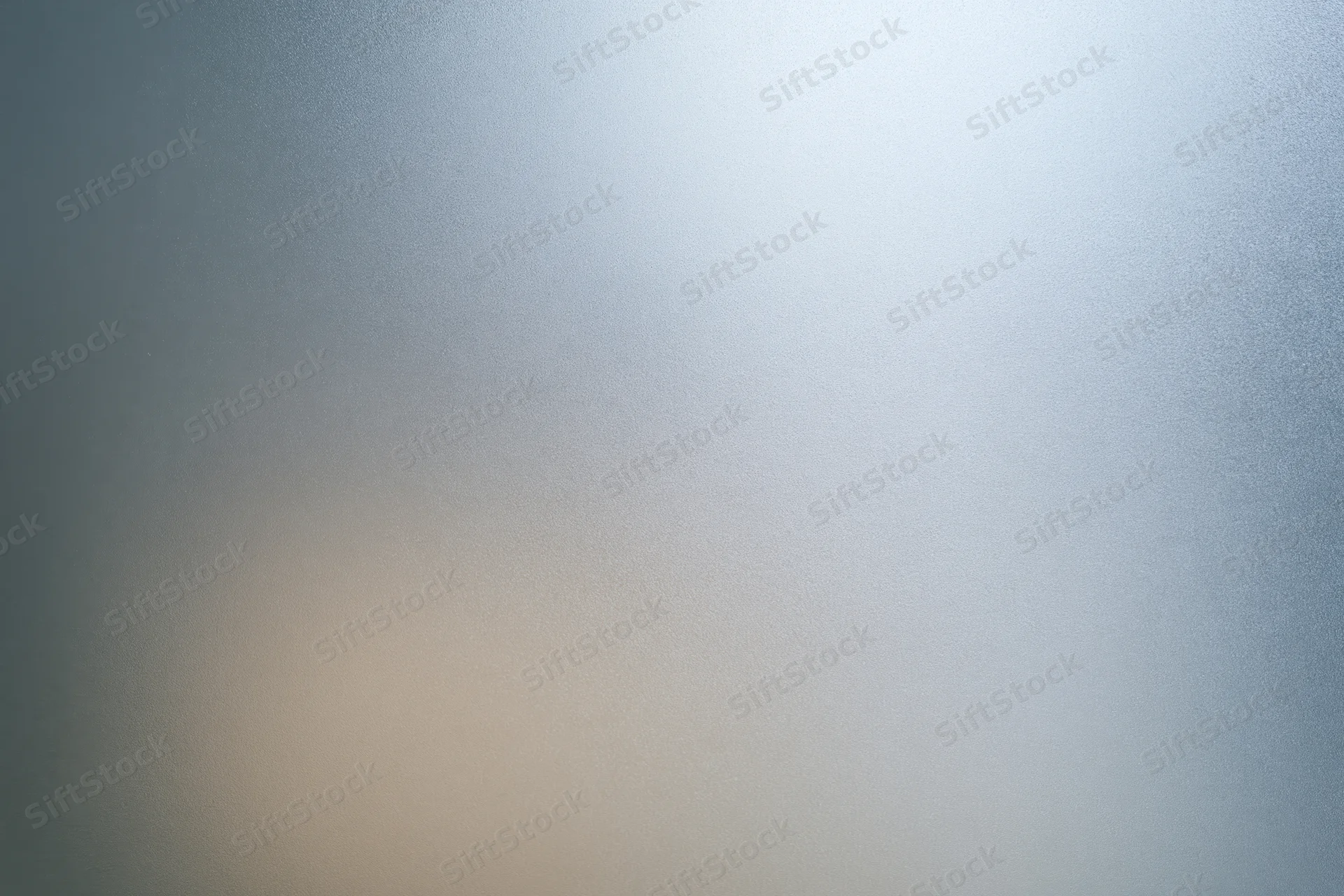 Close-up of a frosted glass surface with a smooth gradient of blue and beige tones