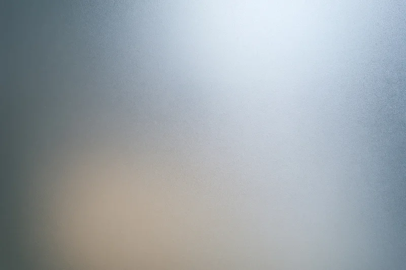 Close-up of a frosted glass surface with a smooth gradient of blue and beige tones