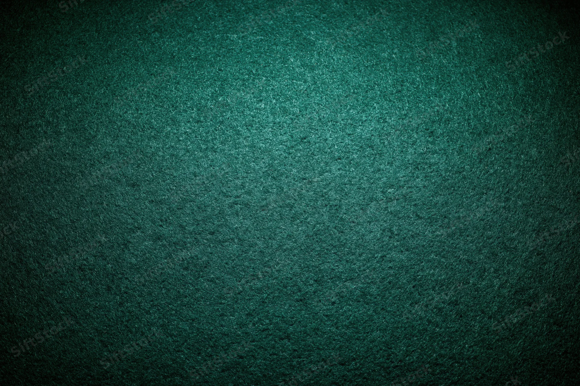 Close-up flat lay of green felt poker table surface with textured grain and dim lighting