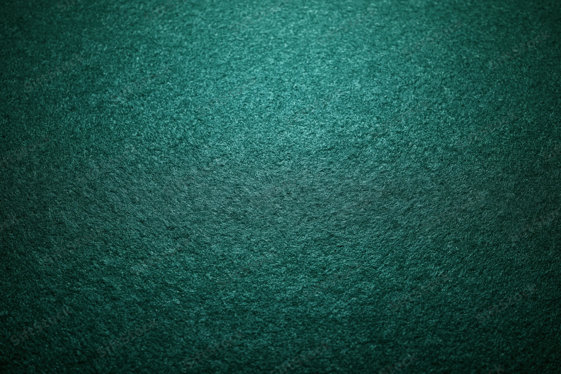 Close-up flat lay of green felt poker table surface with textured weave and subtle lighting gradient