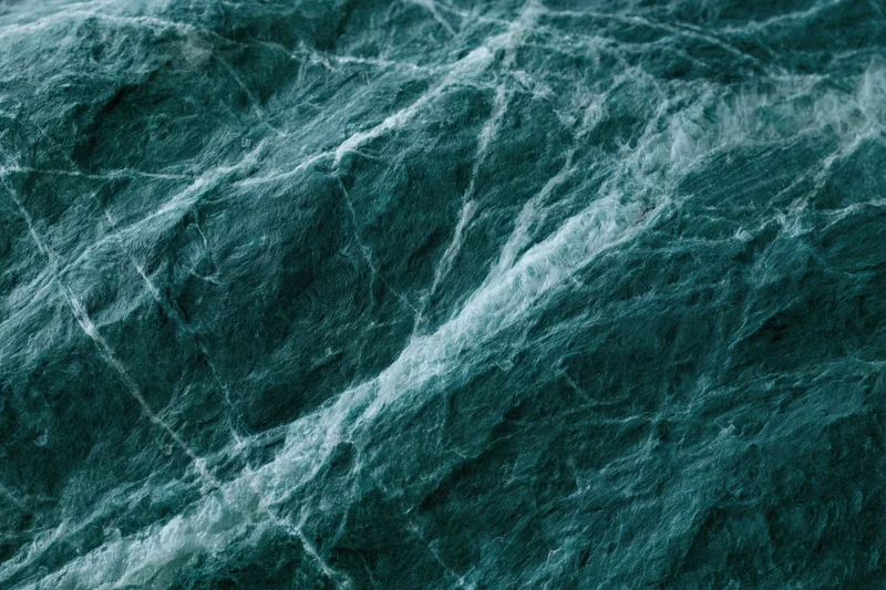 Polished dark emerald green marble slab with natural veining in flat lay view