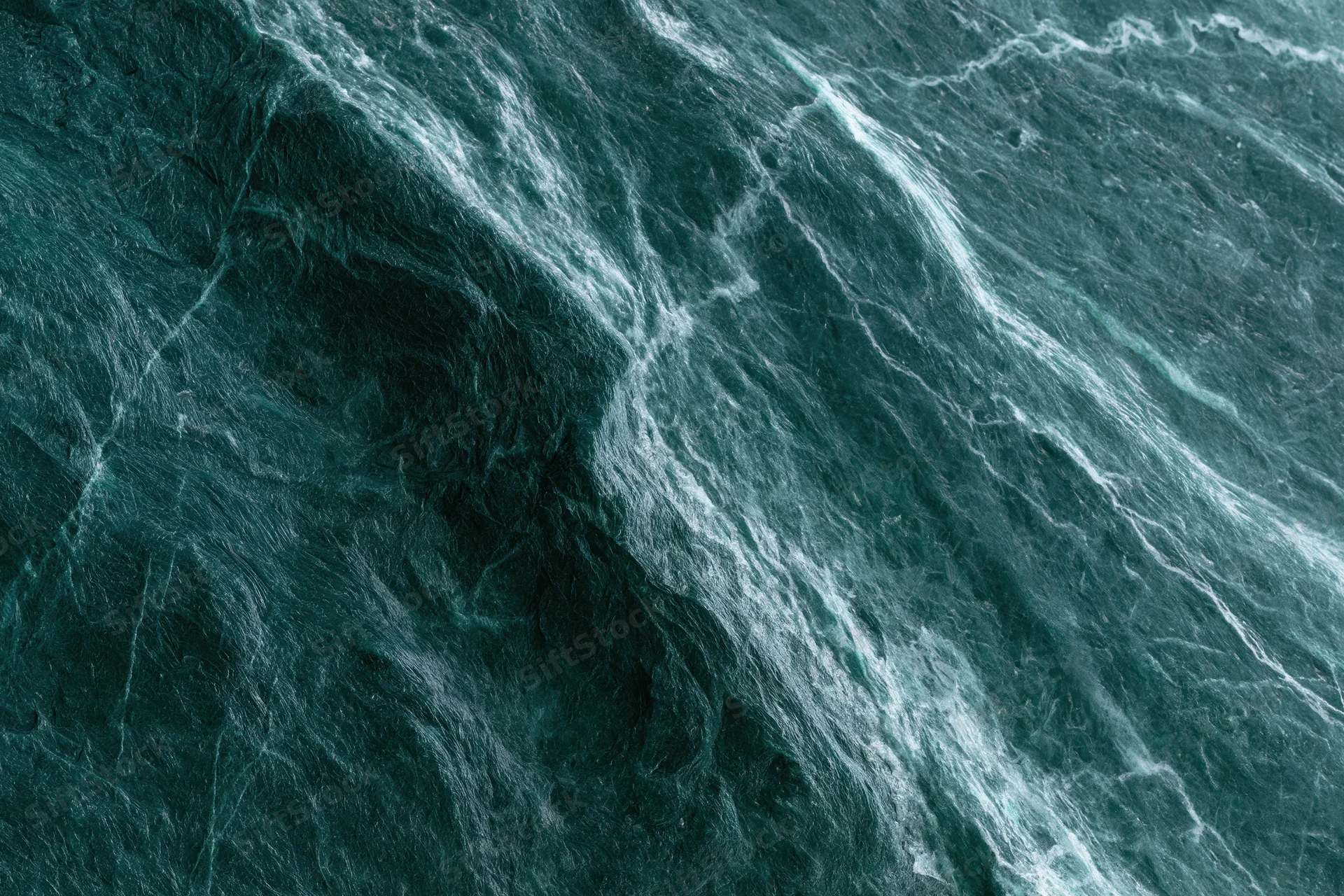 Polished dark emerald green marble slab with natural veining and glossy surface
