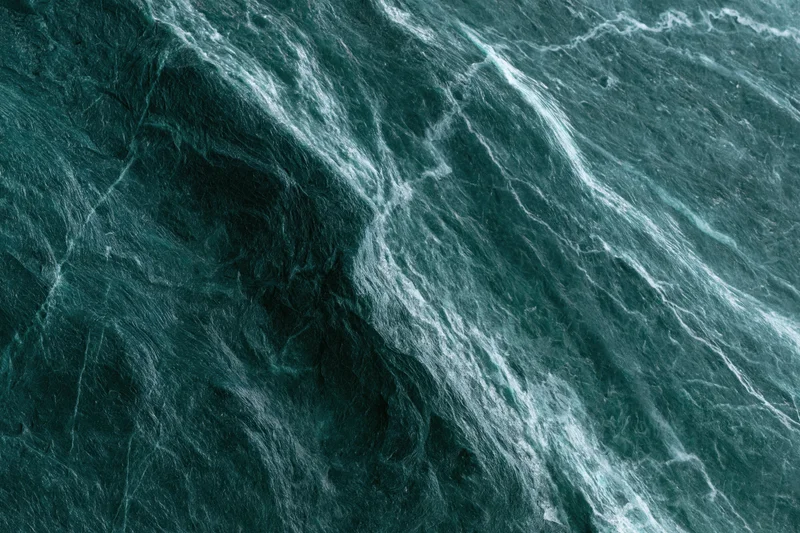 Polished dark emerald green marble slab with natural veining and glossy surface