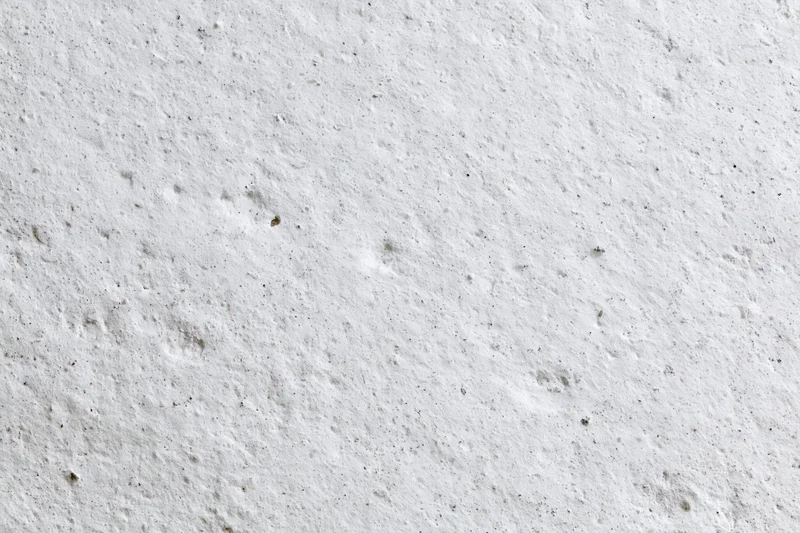 Close-up of rough white concrete wall surface with visible texture and imperfections