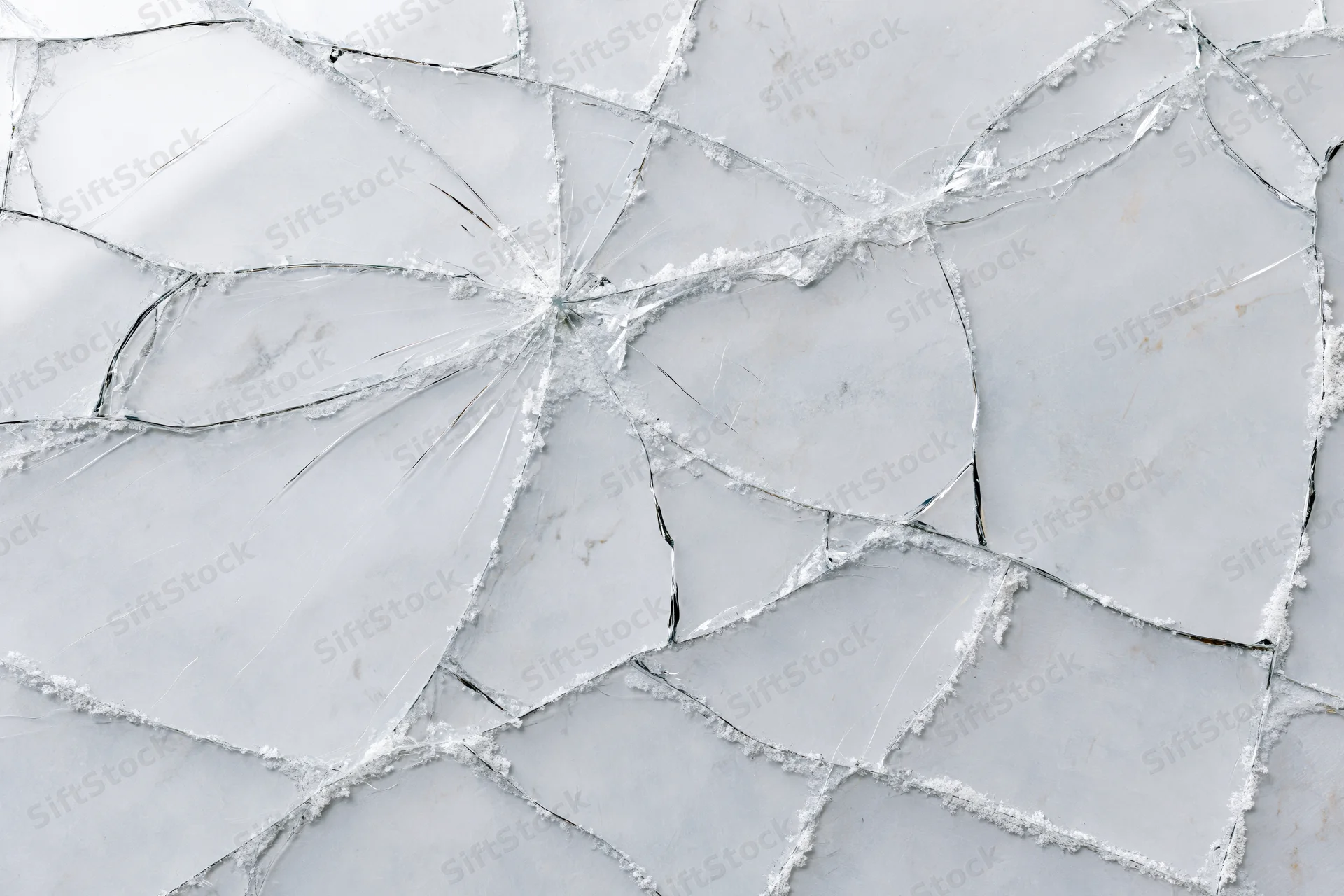 Shattered glass pane with spiderweb cracks in a flat lay arrangement