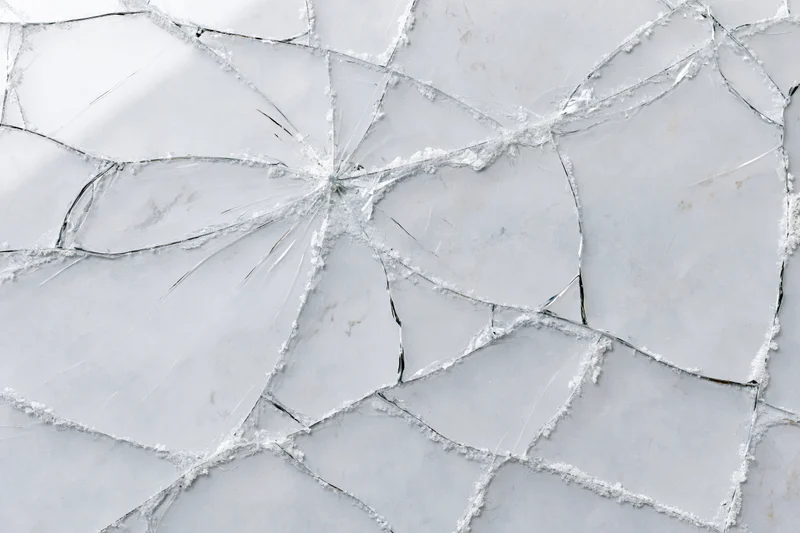 Shattered glass pane with spiderweb cracks in a flat lay arrangement