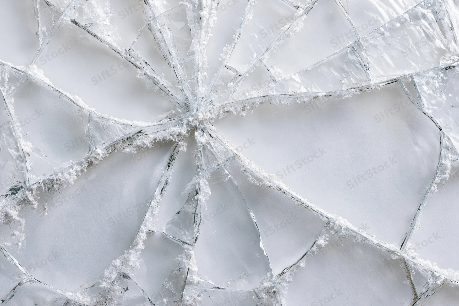 Shattered glass pane with spiderweb cracks in flat lay closeup view