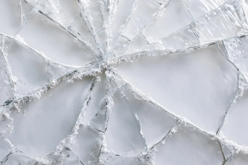 Shattered glass pane with spiderweb cracks in flat lay closeup view