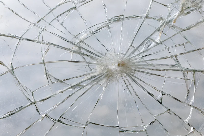 Shattered glass pane with radial cracks in flat lay view