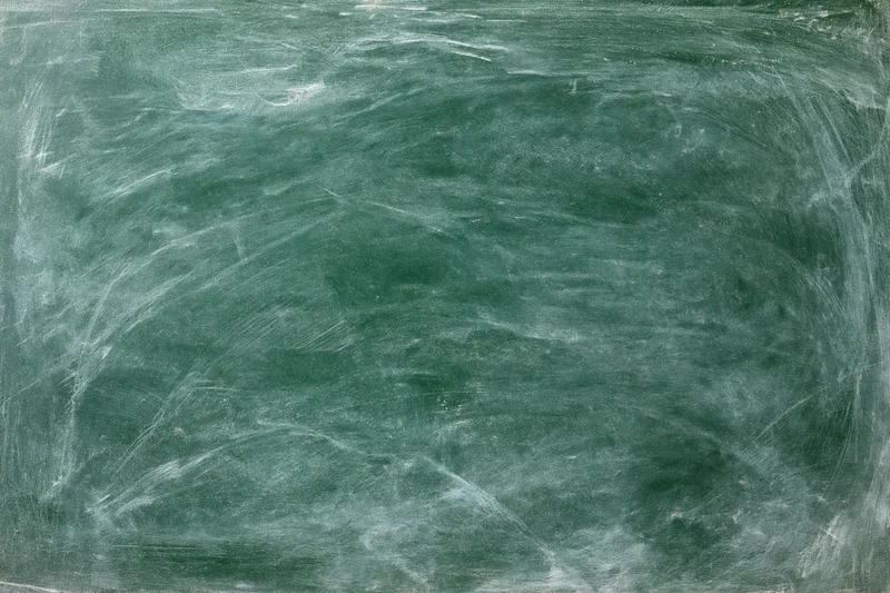 Worn green chalkboard surface with white chalk residue and smudges filling the frame