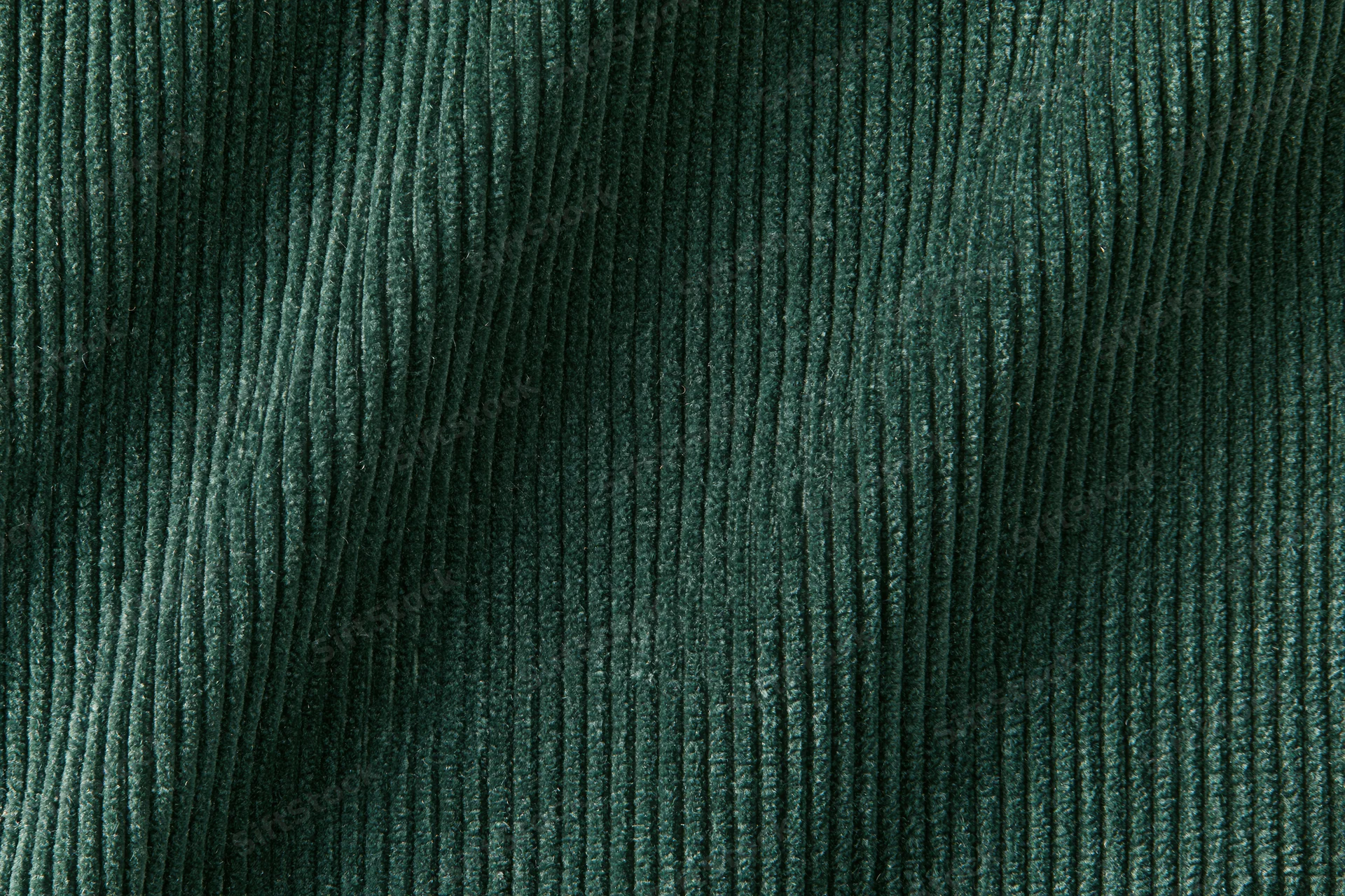Close-up flat lay of dark forest green corduroy fabric filling the frame