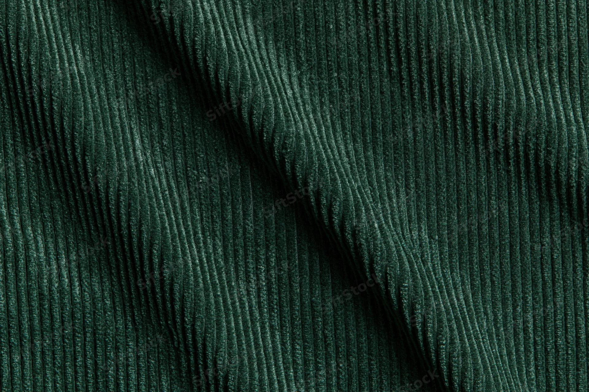 Close-up flat lay of dark forest green corduroy fabric filling the frame