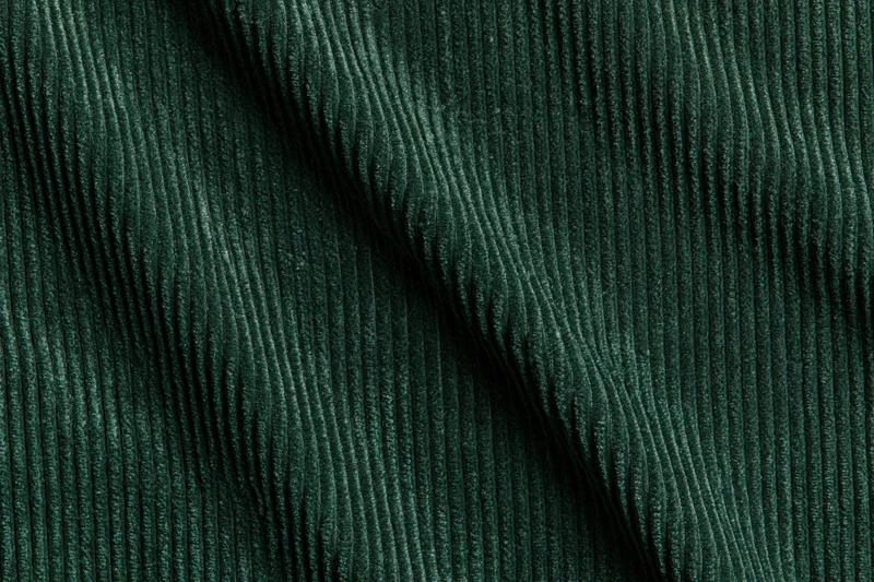 Close-up flat lay of dark forest green corduroy fabric filling the frame