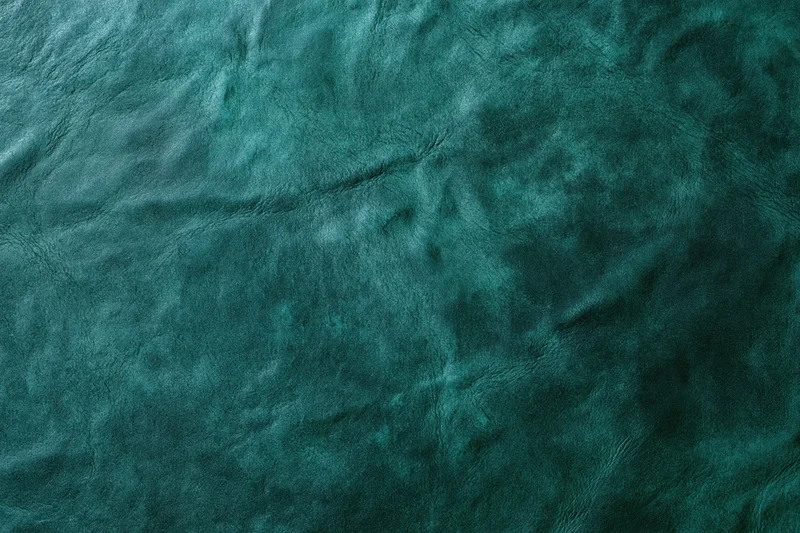 Close-up flat lay of dark forest green leather or suede surface showing natural texture and wrinkles