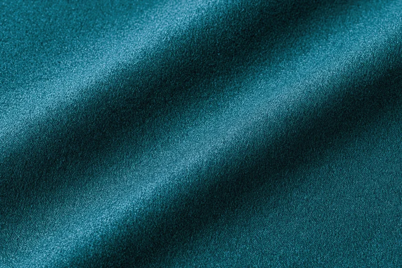 Close-up flat lay of deep teal fabric filling the entire frame