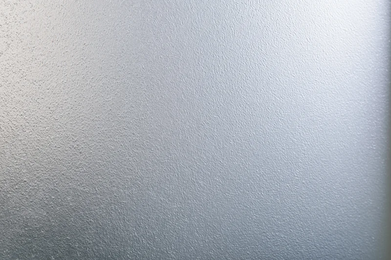 Frosted glass surface with smooth matte texture filling the frame in a flat lay view