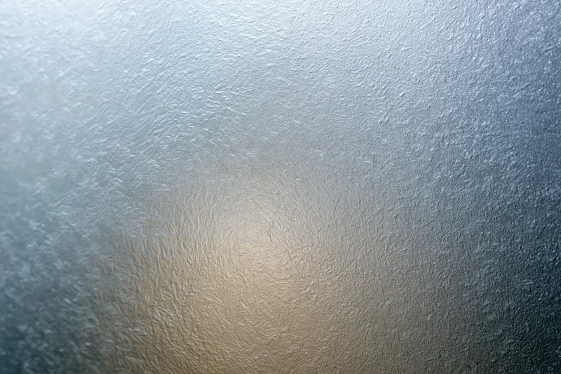 Frosted glass surface with textured pattern and soft light gradient filling the frame