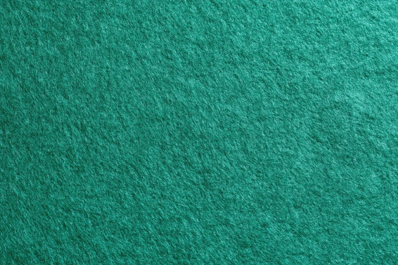 Green felt fabric surface in flat lay closeup filling frame