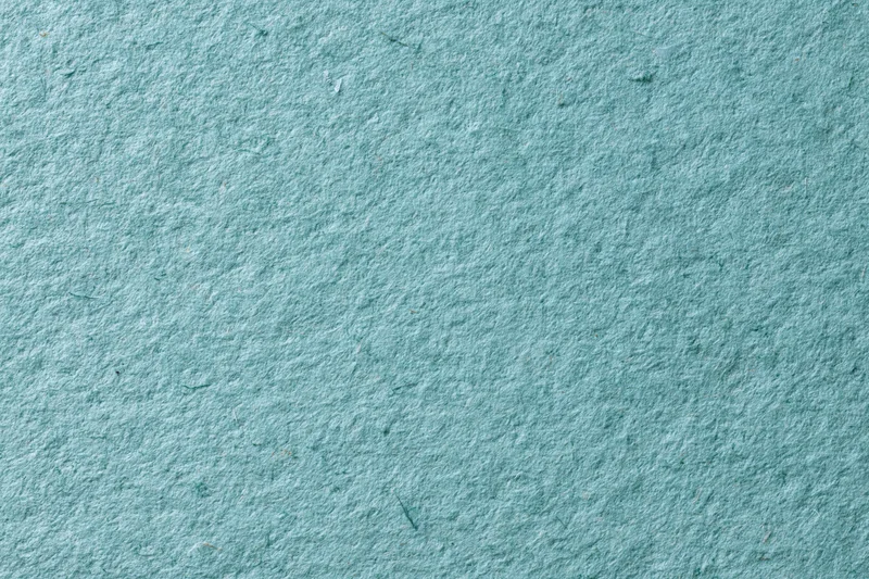 Close-up flat lay of green recycled cardstock paper filling the frame with visible texture and fibers