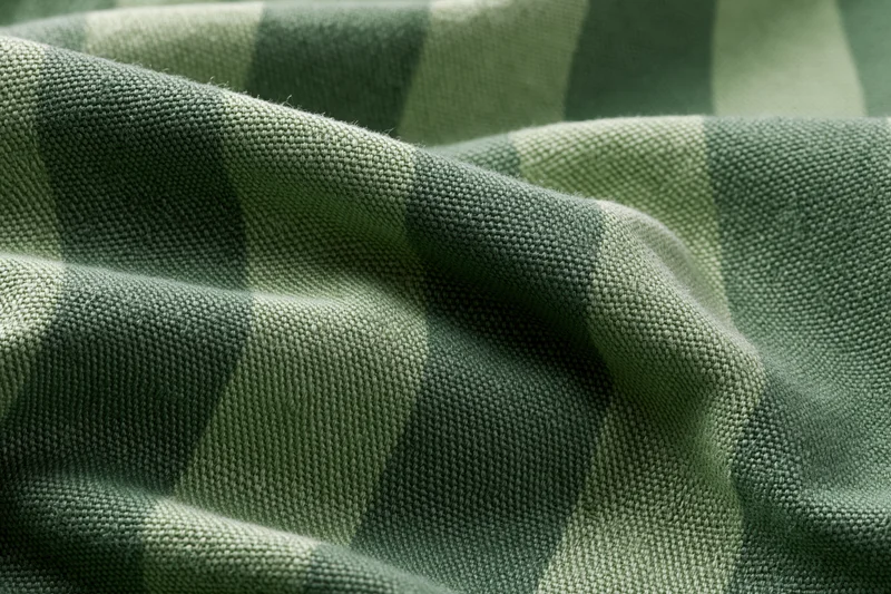 Close-up of green striped fabric textile with woven texture filling the frame