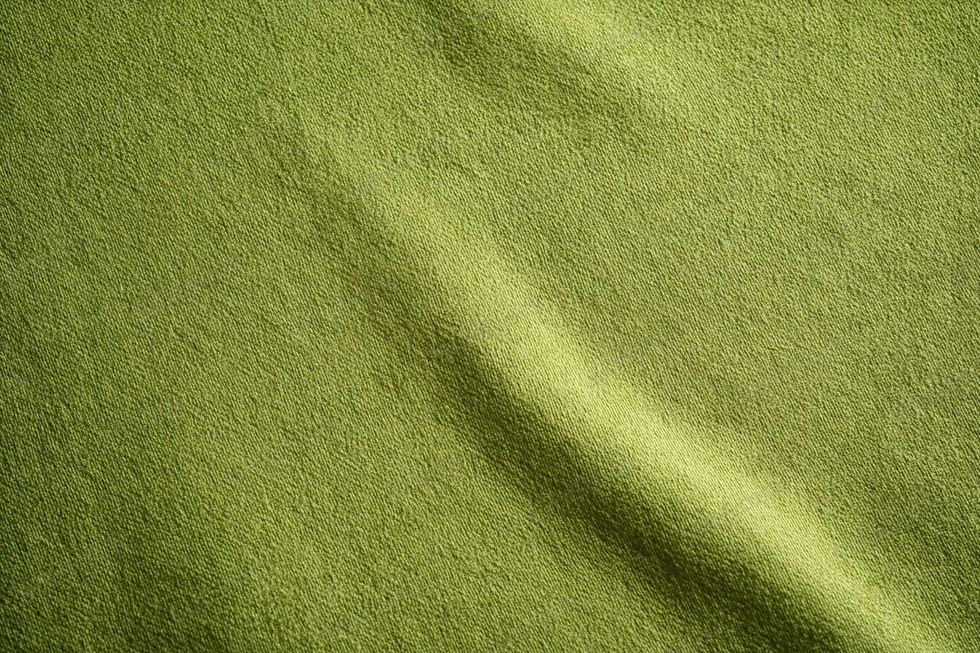 Medium-green fabric surface in flat lay with visible texture and slight folds