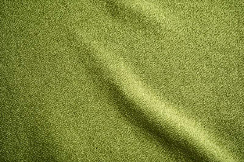 Medium-green fabric surface in flat lay with visible texture and slight folds