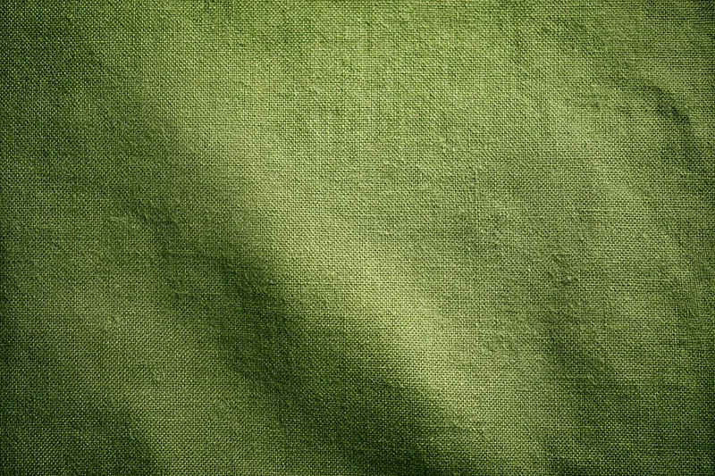 Close-up flat lay of medium-green woven fabric surface filling the frame