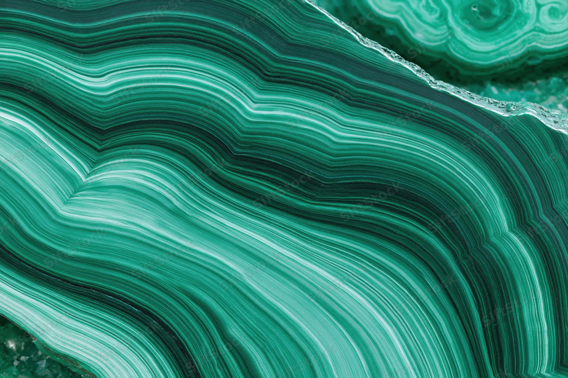 Polished malachite stone surface with concentric green banding filling the frame
