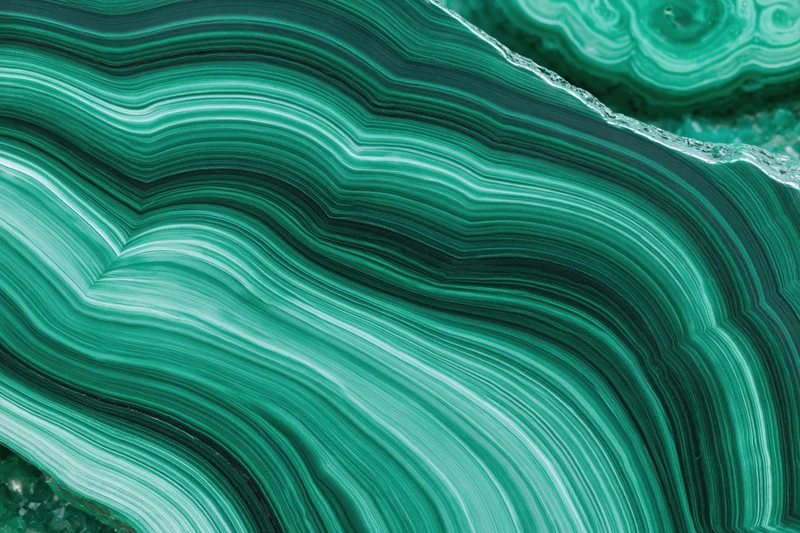 Polished malachite stone surface with concentric green banding filling the frame