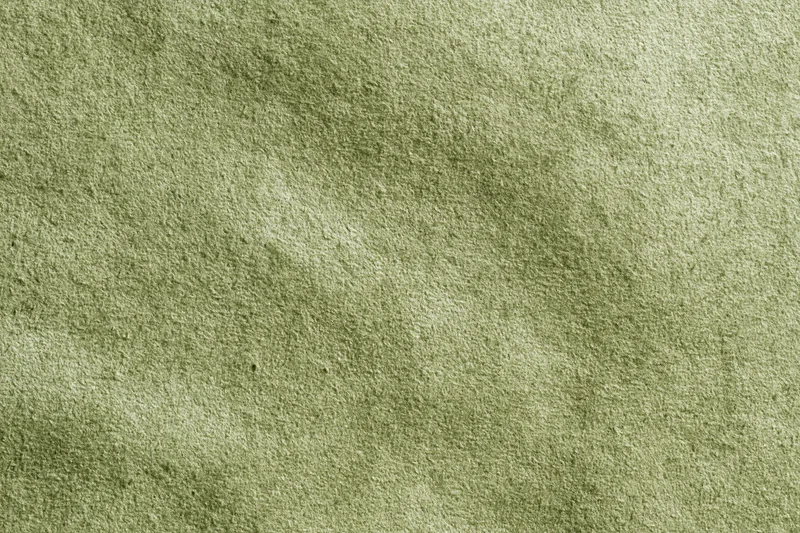 Close-up flat lay of sage green suede or velvet fabric filling the frame