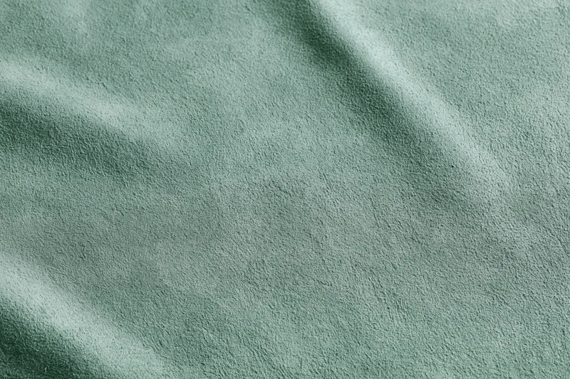 Close-up flat lay of sage green suede or velvet fabric texture filling the frame