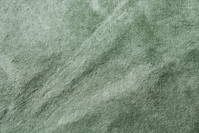 Close-up flat lay of sage green suede or velvet fabric filling the frame