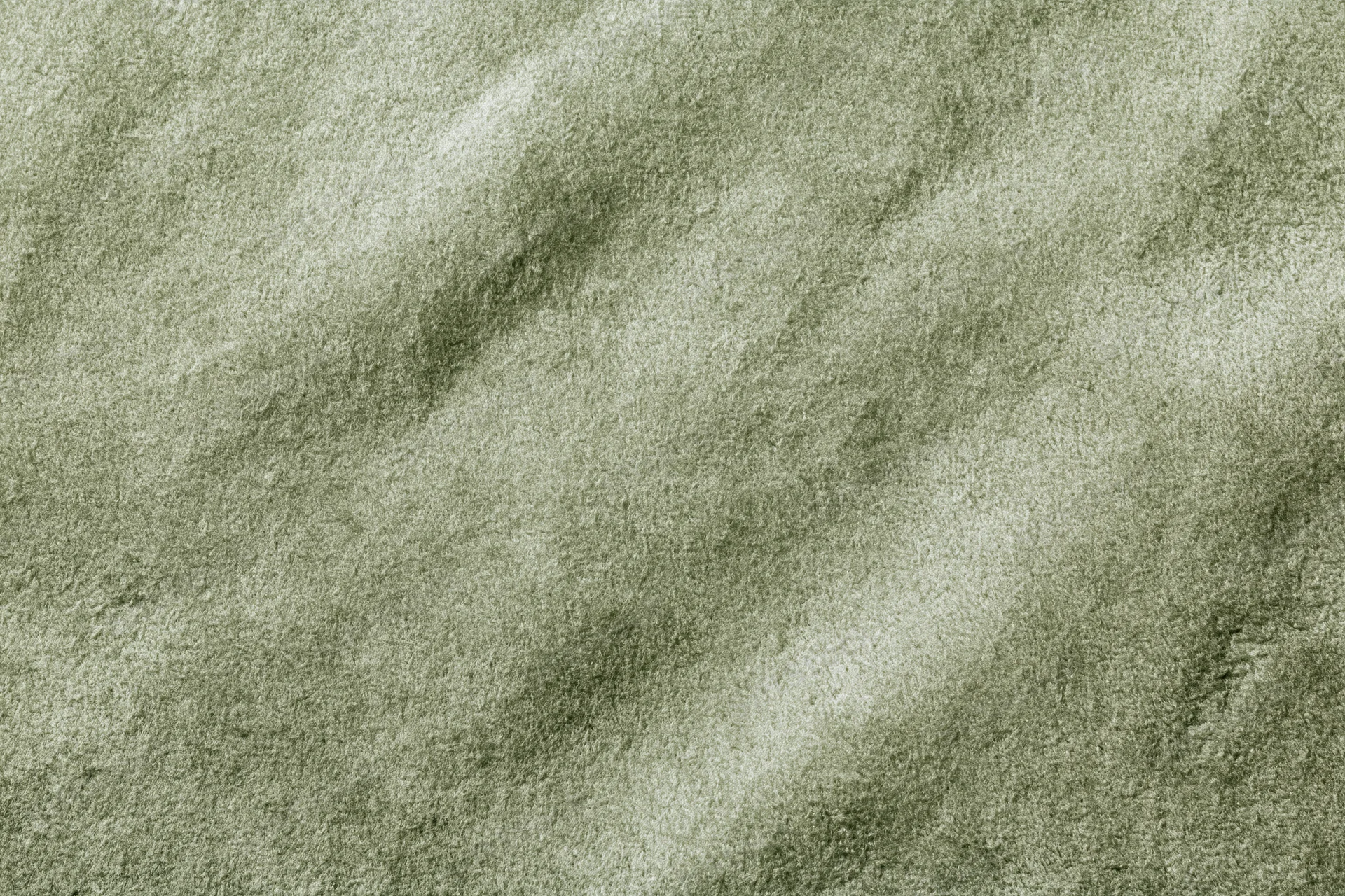 Close-up flat lay of sage green suede or velvet fabric filling the frame