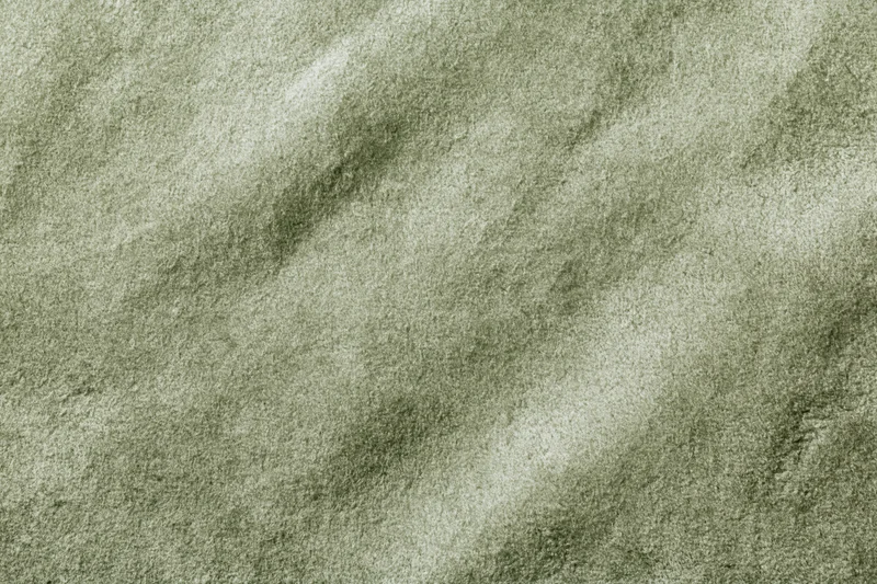 Close-up flat lay of sage green suede or velvet fabric filling the frame