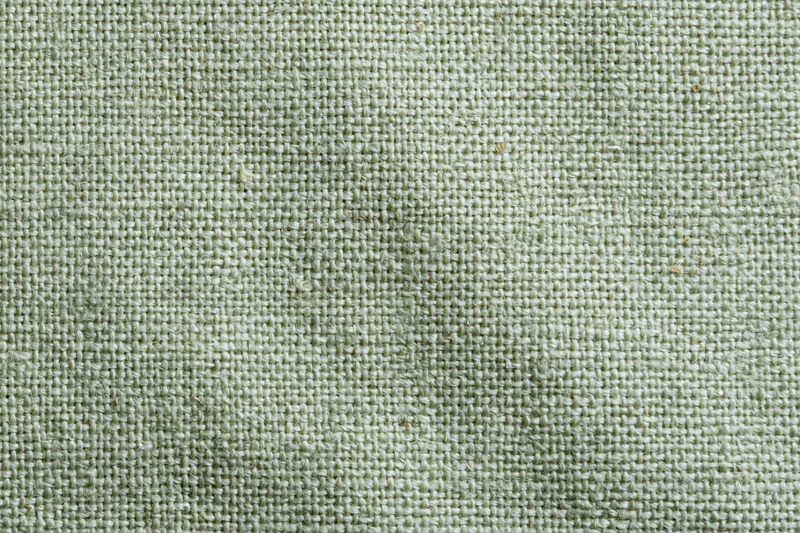Close-up flat lay of sage green woven fabric texture filling the frame