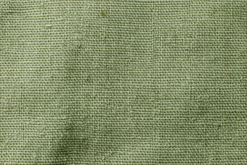 Close-up flat lay of sage green woven fabric texture filling the frame