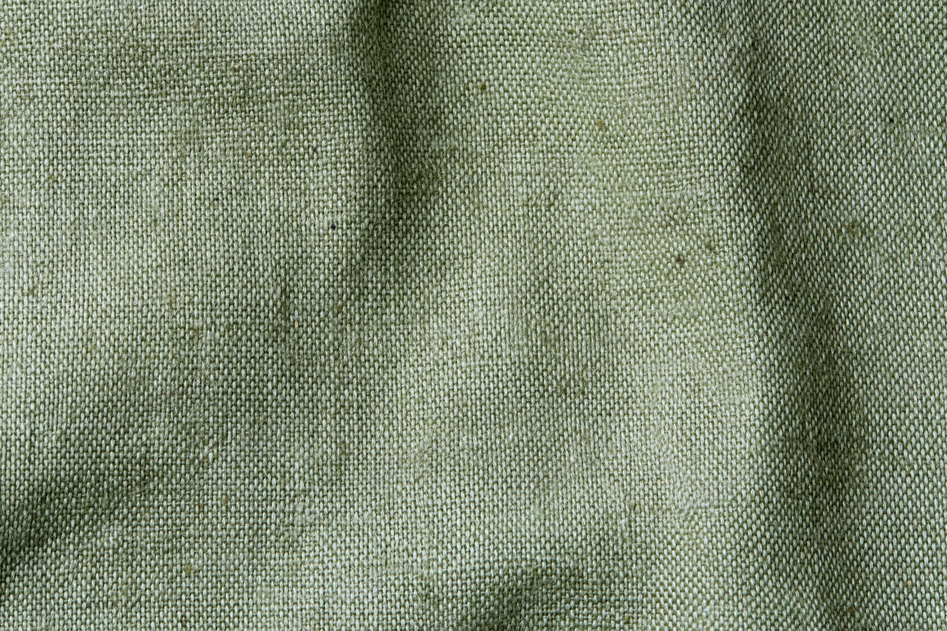 Close-up flat lay of sage green woven fabric texture filling the frame