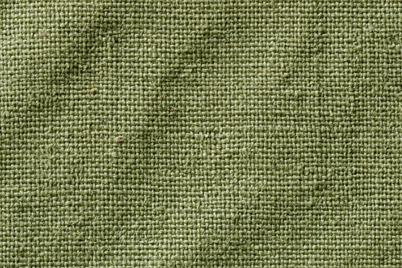 Close-up flat lay of sage green woven fabric texture filling the frame