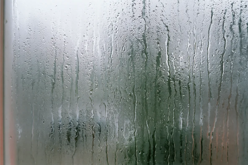 Fogged window glass covered in vertical water streaks and droplets from condensation