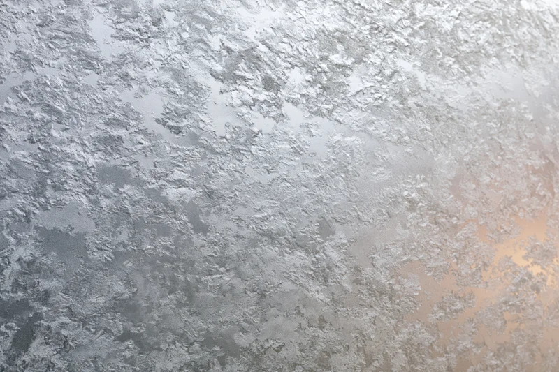 Frosted glass surface with icy crystalline texture and subtle color gradient