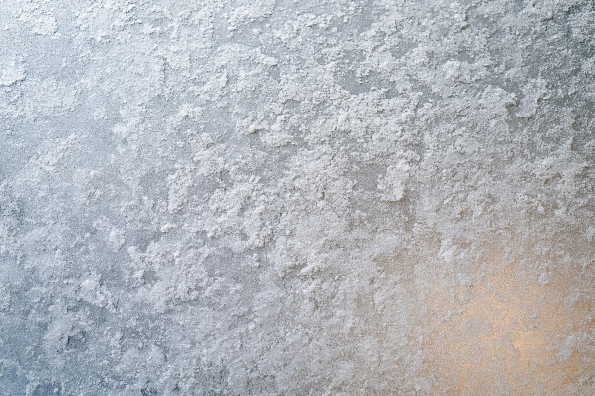 Frosted glass surface with icy crystalline texture and soft warm light gradient