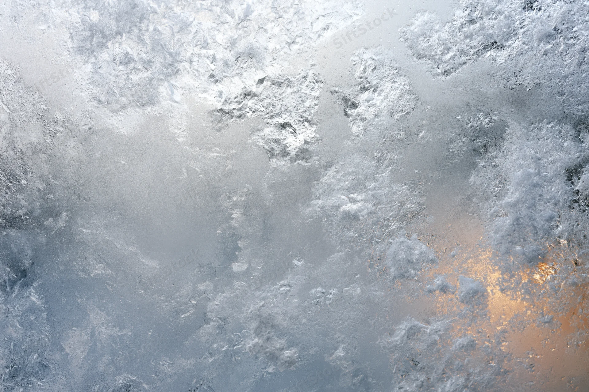 Frosted glass surface with icy crystalline patterns and warm light reflection