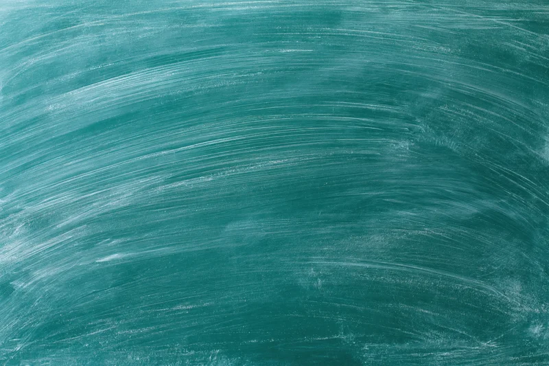 Close-up of a green chalkboard surface with smudged white chalk residue after erasing