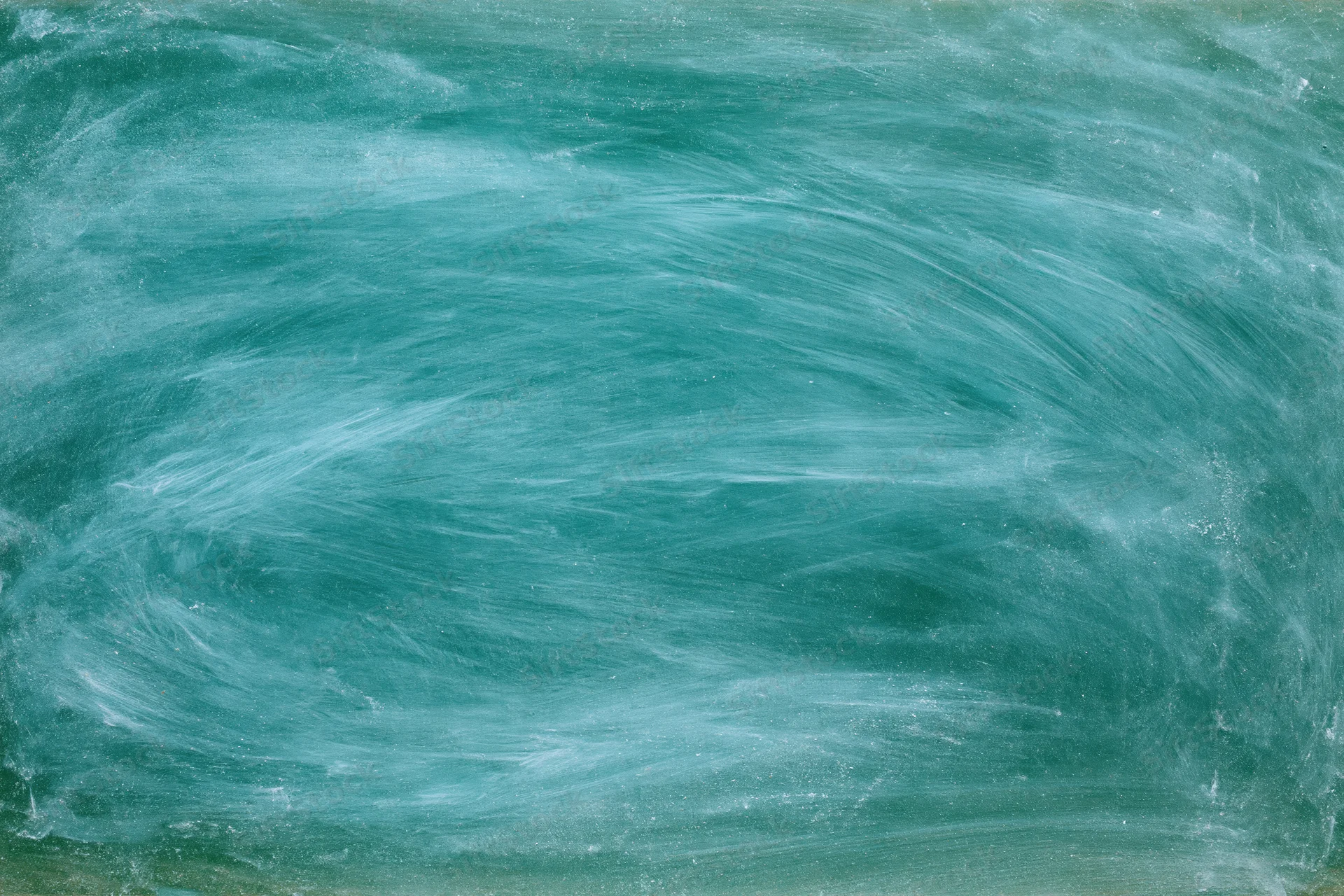 Close-up of a green chalkboard surface with smudged chalk residue and eraser marks