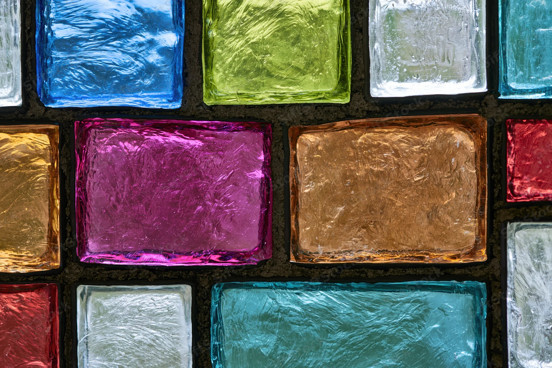 Close-up of a colorful stained glass panel arranged in a grid pattern with textured glass squares in various hues
