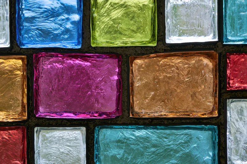Close-up of a colorful stained glass panel arranged in a grid pattern with textured glass squares in various hues