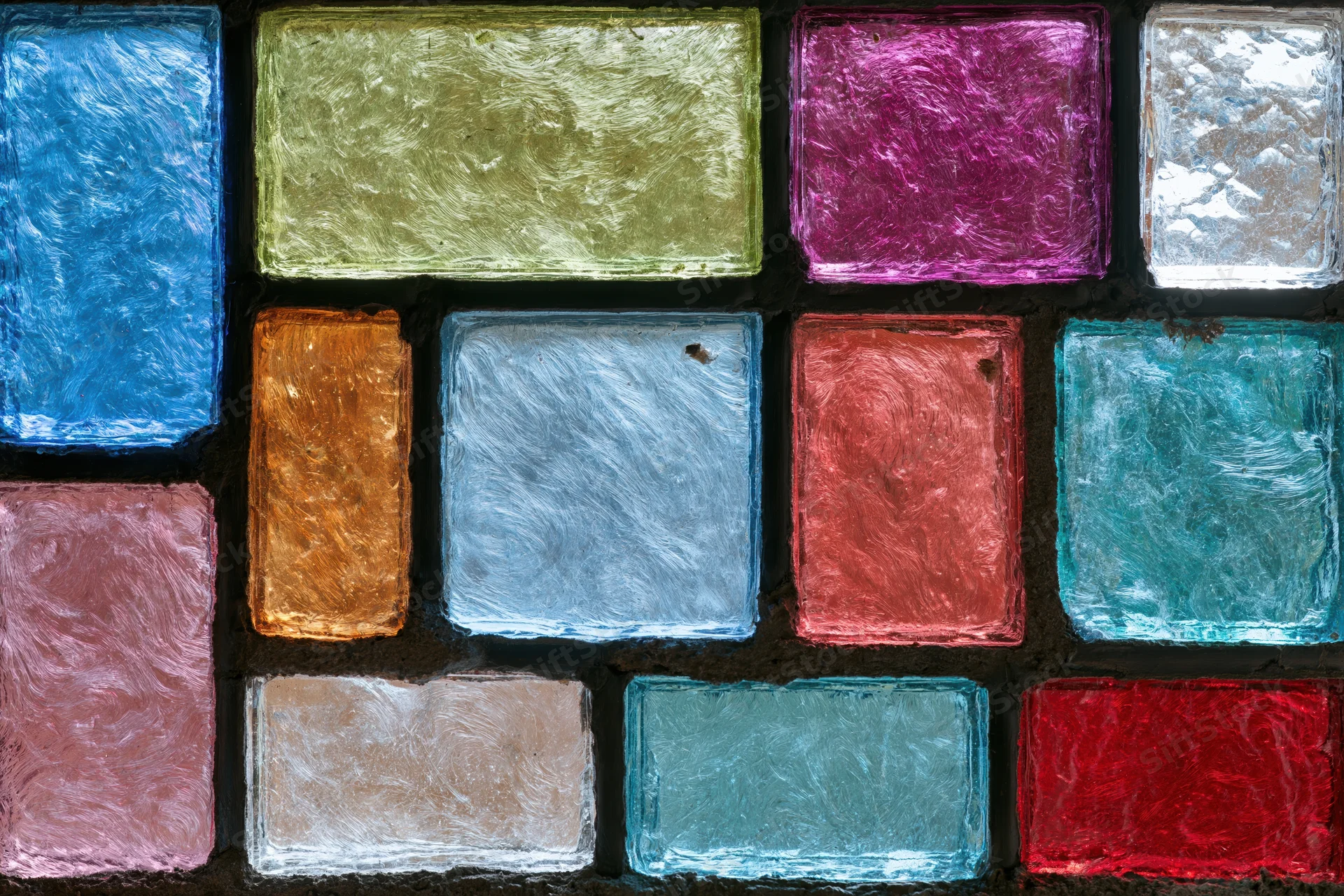Close-up of a stained glass panel arranged in a grid with colorful textured glass pieces